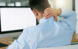Man sitting at desk feeling strain in his neck