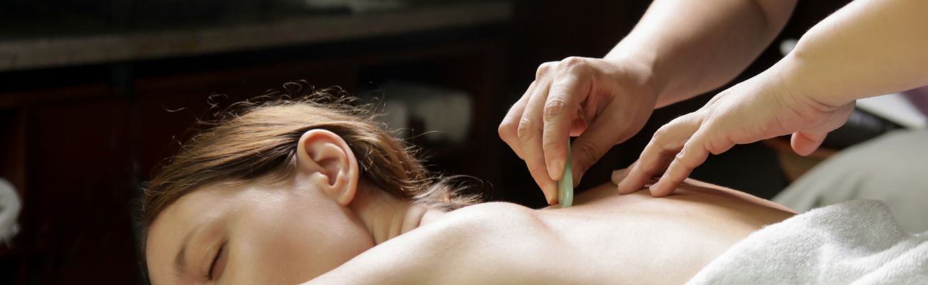 Gua sha therapy using jade on woman's back